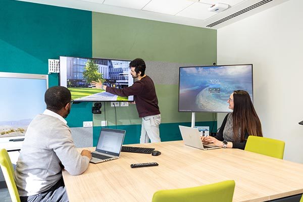Hybrid working environment with three people and display screens