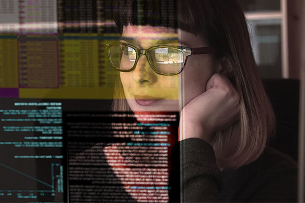 Person looking at computer, code reflected in glasses