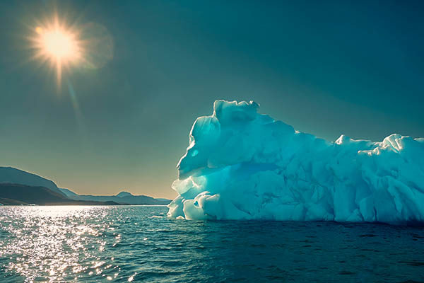 Iceberg in ocean with sun